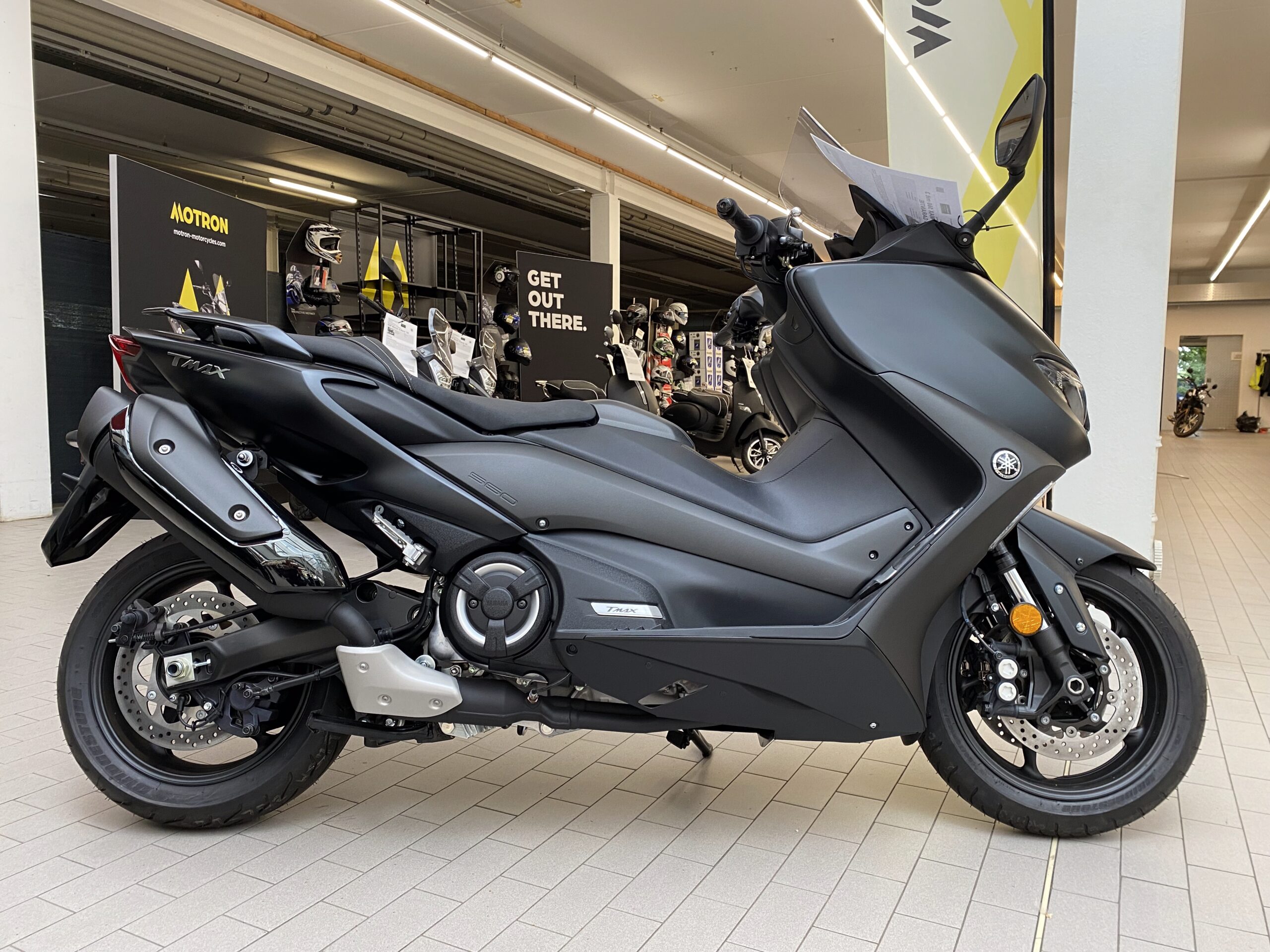Black Yamaha T Max in the showroom, Scooter taken from the side, free-standing and without a cover.